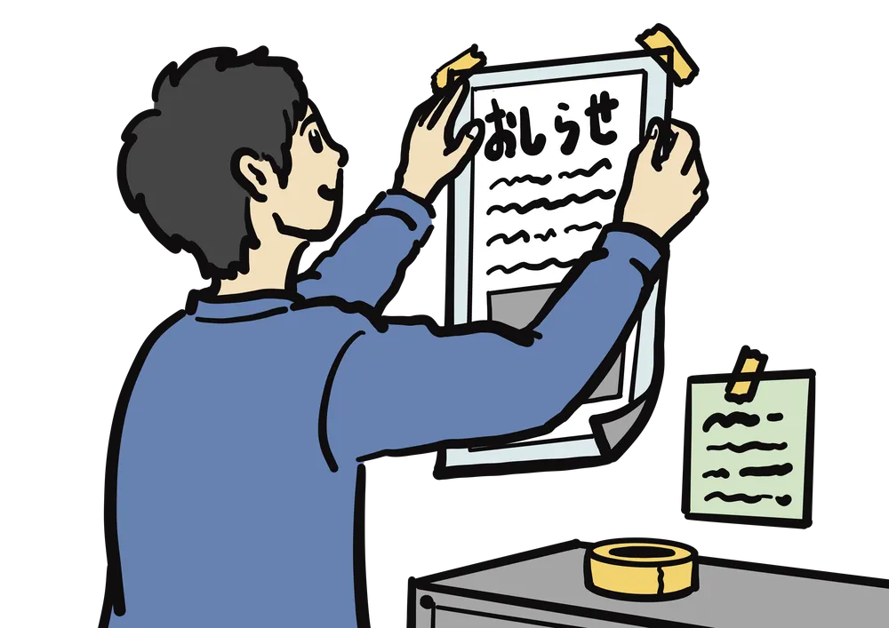 壁にお知らせのポスターをテープで貼る様子