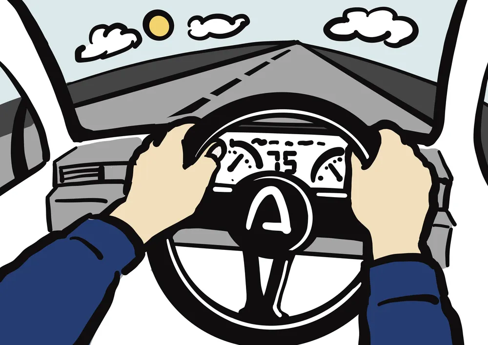 車のハンドルを握る両手。車内から車外が見える。運転からの景色。